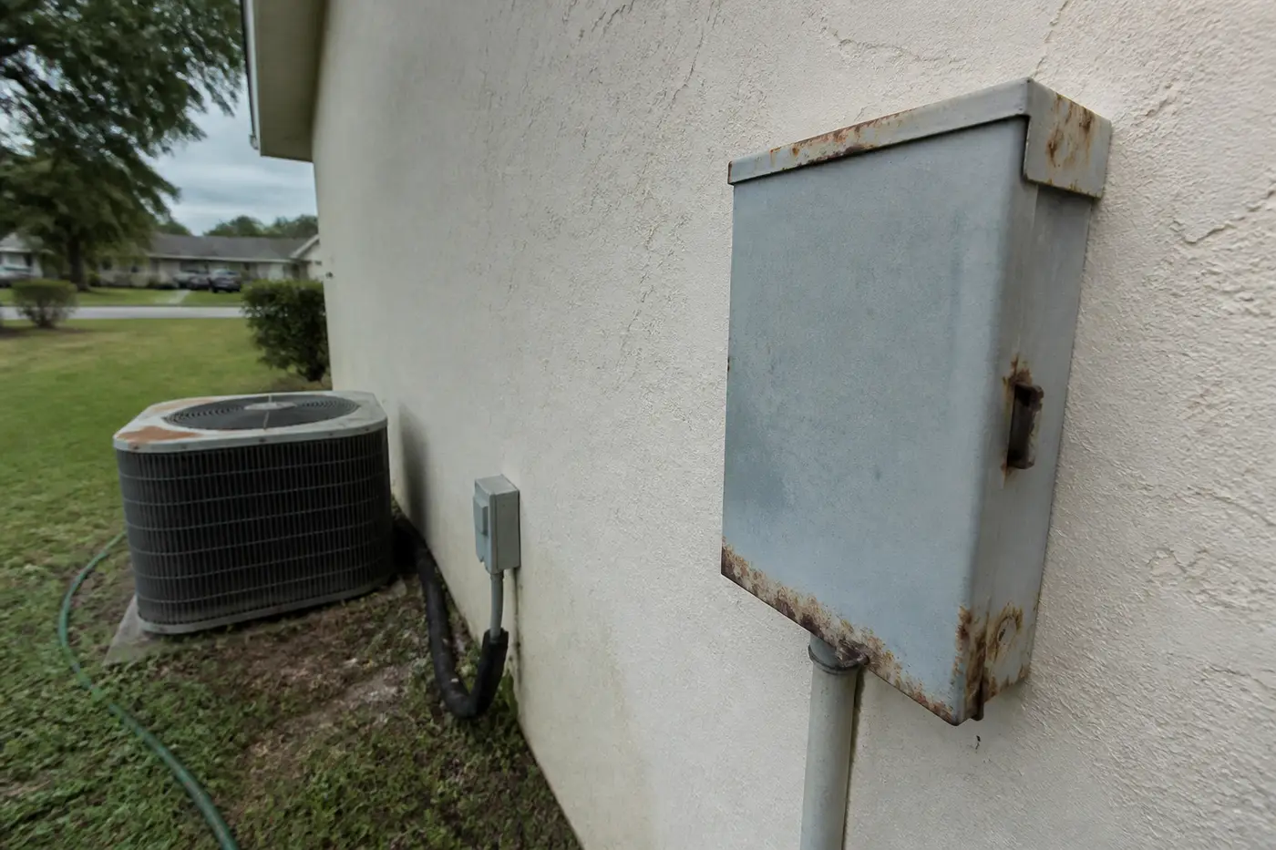 Rusty AC disconnect beside an old condenser, typical wear after 15 years in Florida